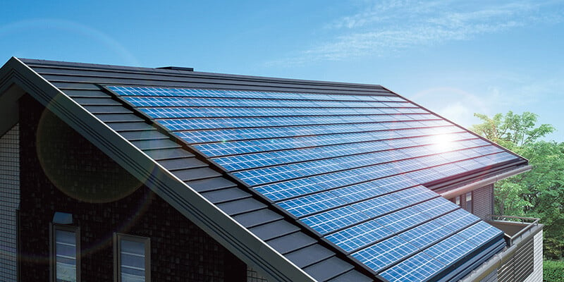 A photo of a modern residential home with a series of solar panels mounted on the rooftop.