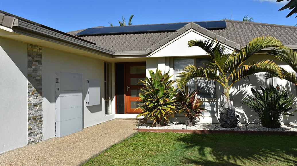 A house with Panasonic EVERVOLT solar panels installed on the roof, plus an EVERVOLT home battery storage unit installed on the side of the home